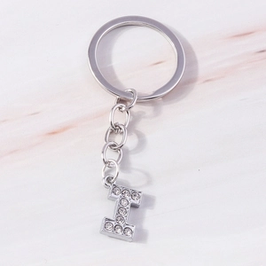 Macro detail of silver alphabet I keychain with sparkling crystals on marble