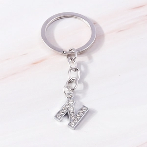 Detail of silver letter N keychain encrusted with sparkling white rhinestones on marble