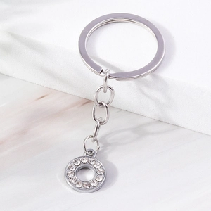 Close-up of polished silver keychain with sparkling rhinestones on marble background