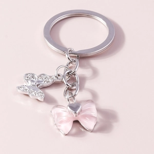Eleganter rosa Schmetterlings-Schlüsselanhänger mit Strass und Harzschleife auf rosa Hintergrund