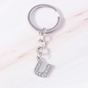 Macro view of silver alloy letter U keychain with sparkling rhinestones and metal ring