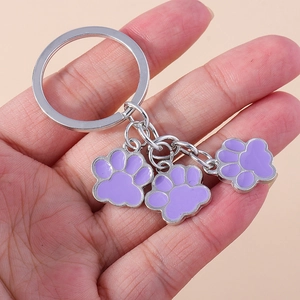 Détail d'un porte-clés en métal avec trois breloques de pattes en émail violet