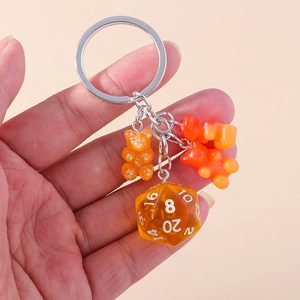 Detailed shot of translucent orange D20 dice and gummy bear charms on a silver keychain