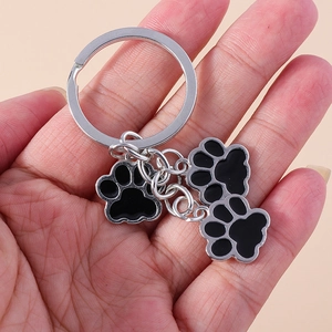 Détail d'un porte-clés en métal argenté avec trois breloques de pattes d'animaux noires