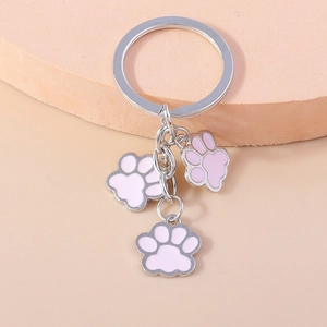 Porte-clés créatif en métal avec trois pattes en émail rose et anneau argenté sur fond rose