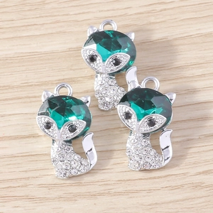 Detailed close-up of three fox charms with green gemstones and white rhinestones