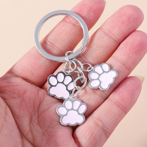 Gros plan d'un porte-clés en métal avec trois pendentifs pattes de chat roses polis