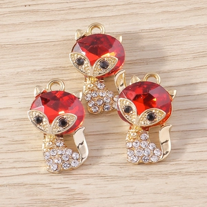 Detailed close-up of cute cartoon fox charms with red rhinestones and golden alloy for DIY