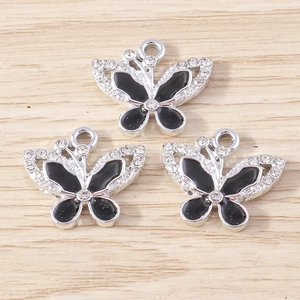Tre eleganti ciondoli a farfalla in argento con smalto nero e strass su fondo in legno