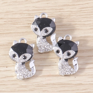 Macro detail of fox jewelry pendants with black faceted gems and sparkling white rhinestones