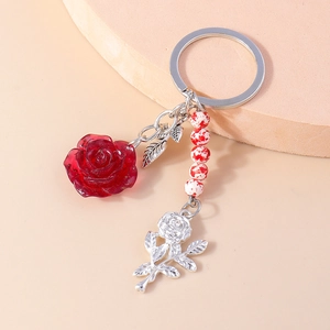 Elegant red resin rose keychain with silver leaf and beaded chain on neutral background