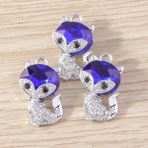 Detailed view of silver fox charms with blue faceted gems and small white diamonds