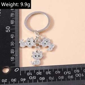 Close-up of silver cat keychain with crystals showing 9.9g weight and size scale