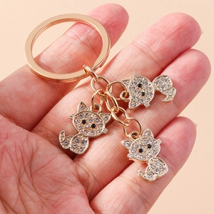 Classic rose gold cat keychain with three rhinestone-studded charms in palm view