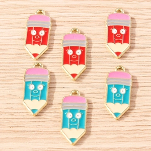 Macro shot of pencil-shaped enamel pendants with cute cartoon faces and gold borders
