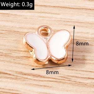 Macro view of a 8mm rose gold butterfly pendant with white enamel detail and top loop