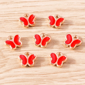 Detailed macro view of seven gold-plated butterfly charms with red enamel and hanging loops