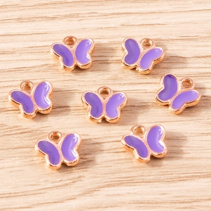Macro detail of seven purple butterfly charms with rose gold bases on wood background