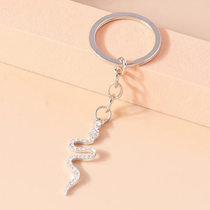 Creative silver snake keychain with white sparkling rhinestones on a minimalist block