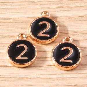 Macro shot of number 2 round alloy charms with black enamel and gold finish for DIY