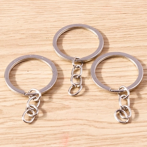 Three minimalist silver alloy keychains with rings and link chains on a wood background