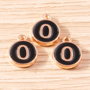 Detail of three rose gold and black enamel number 0 charms for jewelry making