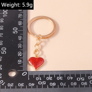 Macro detail of red glitter heart pendant with gold keychain and size measurement