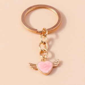 Detail view of a pink heart pendant with gold wings and rose texture on golden keyring