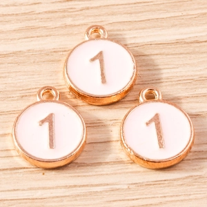 Macro detail of three rose gold number 1 enamel charms on a light wood background