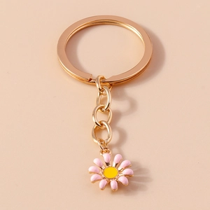 Close-up of pink daisy keychain with rose gold metal ring and vibrant yellow flower center