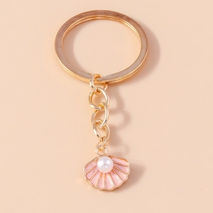 Detail eines rosa Muschel-Schlüsselanhängers mit Goldring und weißem Perlen-Inlay
