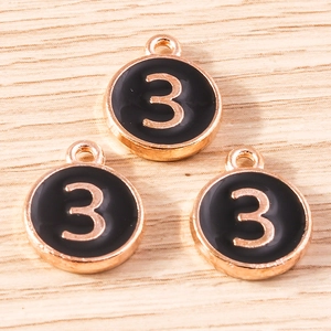 Detailed view of three circular black enamel number 3 pendants with gold alloy plating