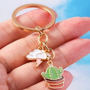 Macro detail of cartoon cloud and cactus charms on a golden metal keychain ring