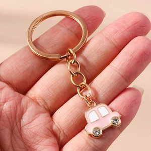 Vue détaillée du porte-clés voiture rose avec roues en cristal et anneau doré poli