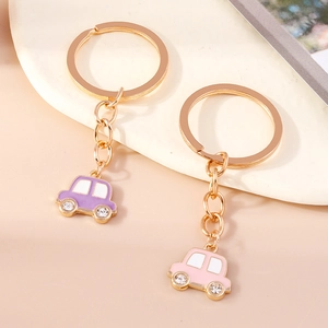 Détail de mignons porte-clés voiture en rose et violet avec strass et anneaux dorés
