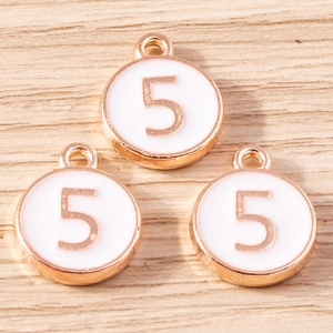 Macro detail of rose gold and white enamel number 5 pendants on a wood surface