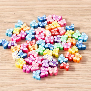 Colorful butterfly polymer clay beads for DIY jewelry making on a light wooden background