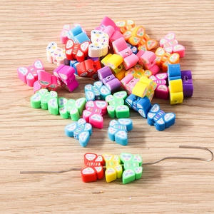 Colorful polymer clay butterfly beads for DIY jewelry making on a light wood background