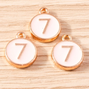 Macro detail of round number 7 charm pendants with rose gold finish and white enamel inlay