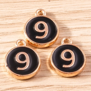 Macro shot of three gold-plated number 9 charms with black enamel finish for DIY jewelry