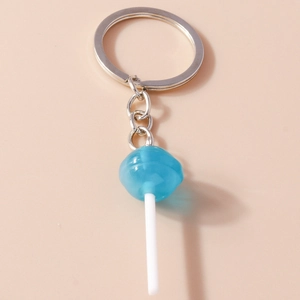 Close-up of blue resin lollipop keychain with silver ring on soft pink background