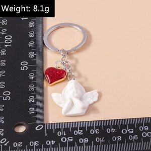Close-up of cute white resin angel keychain with red glitter heart and silver metal ring