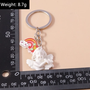 Macro view of a 8.7g white cupid angel keychain with harp and colorful rainbow cloud detail