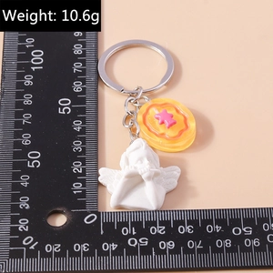 Detail view of a white resin angel keychain and orange flower charm next to a ruler