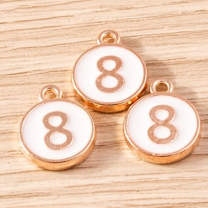 Macro shot of three rose gold number 8 charms with white enamel on a wooden surface