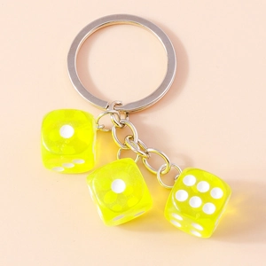 Detailed macro view of three fluorescent yellow resin dice on a silver metal keychain ring