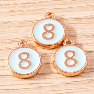 Macro detail of three rose gold number 8 pendants with light blue enamel on wood