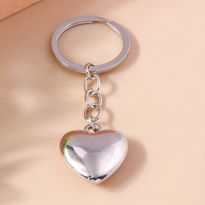 Portachiavi a cuore minimalista con ciondolo in metallo lucido su uno sfondo dai toni caldi
