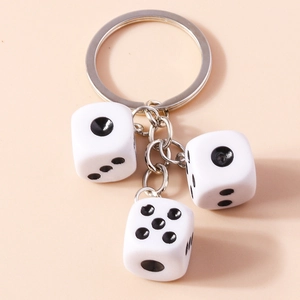 Detail of three white acrylic dice keychain with black pips and silver metal ring