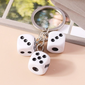 Detail of acrylic dice keychain with silver alloy ring on warm beige background